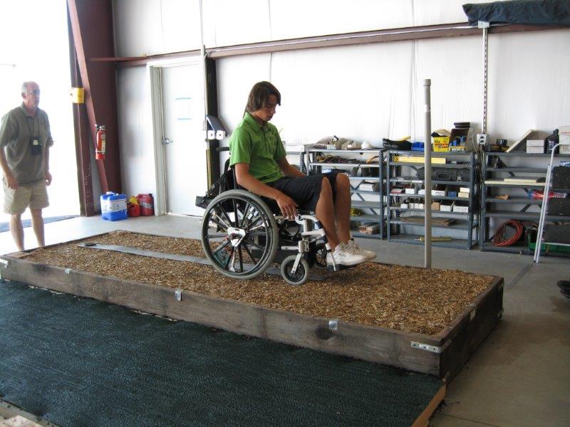 A man in using a manual wheelchair wheels across a sample surface plot in the laboratory.