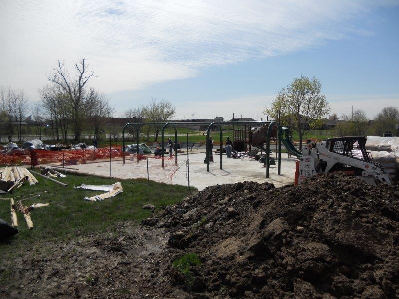 A mound of excavated dirt is shown in the foreground while the new playground construction site is prepared for installation of the surface system.