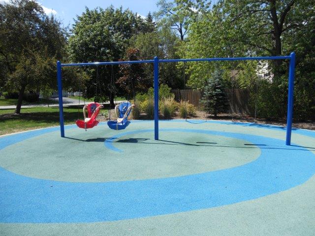 Two hard-back swings over a blue/green poured-in-place rubber surface.