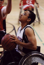 boy in wheelchair shooting basketball on court