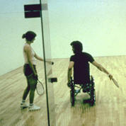 photo of man in wheelchair playing indoor racket ball