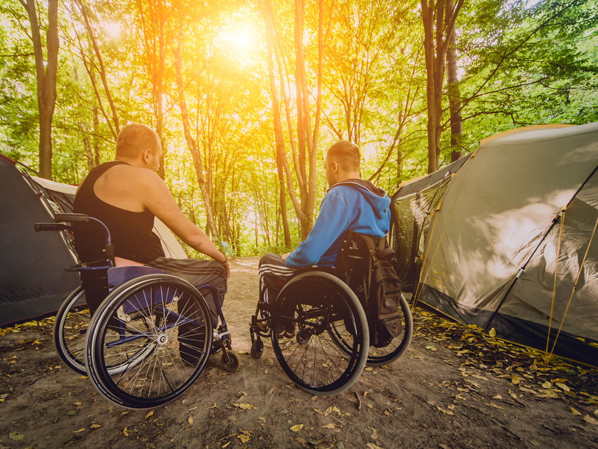two people in wheelchairs at a campsite