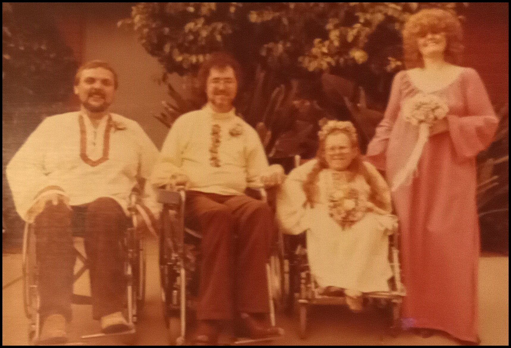 Dennis poses next to three other people. Dennis and two others are wheelchair users.