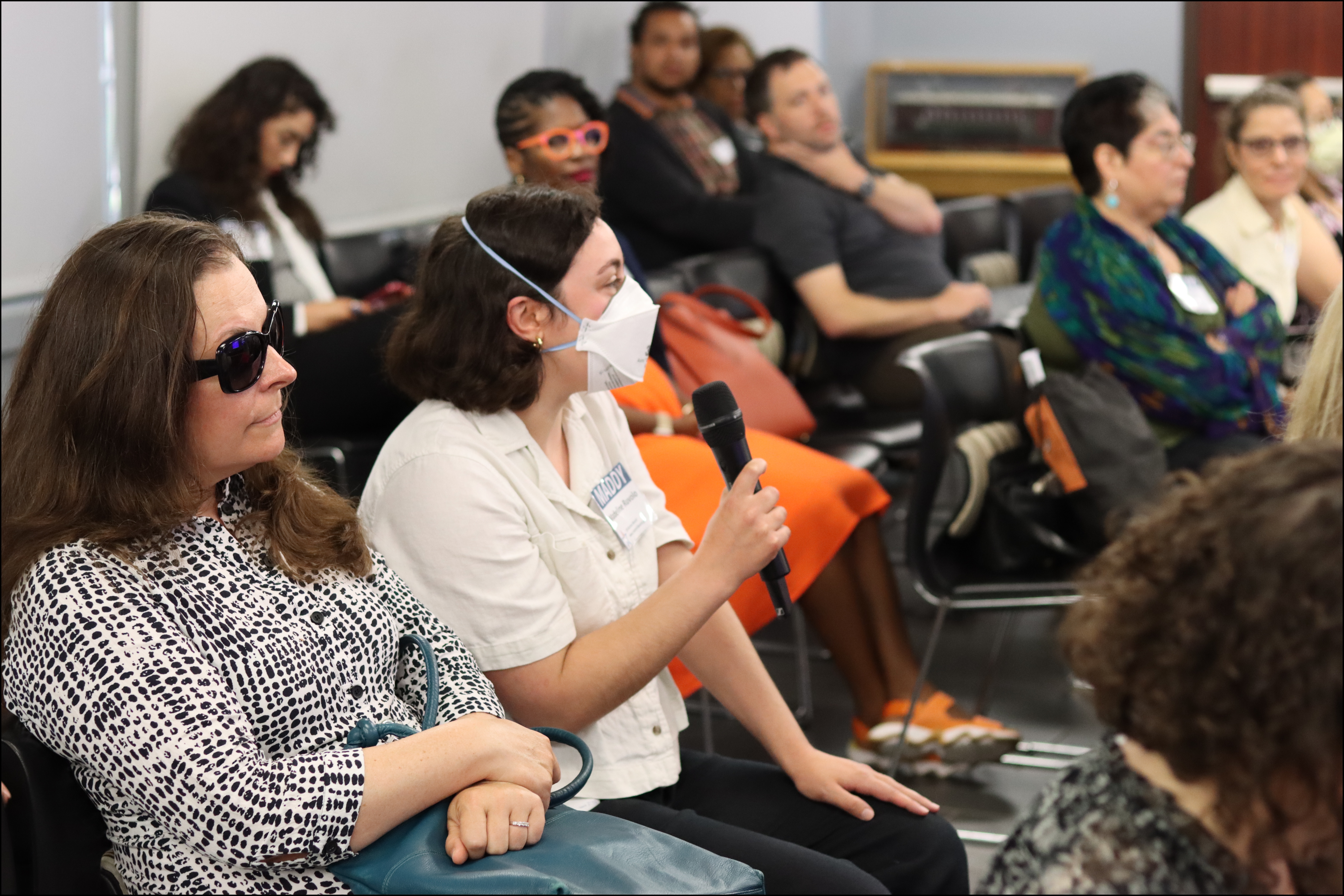 A Board Member speaks into a microphone at a meeting.