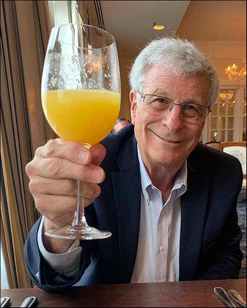 Bobby Silverstein holding a glass of juice and giving a cheers to the viewer.